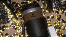 a black and gold stanley coffee mug is surrounded by gold coins