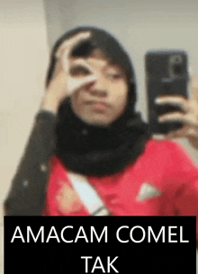 a woman in a hijab is taking a picture of herself in a mirror .