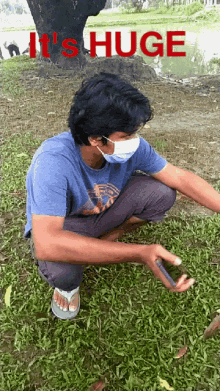 a man wearing a mask is squatting in the grass with the words " it 's huge " written above him