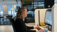 a woman sits at a desk in front of a computer with a mug that says ' im ' on it