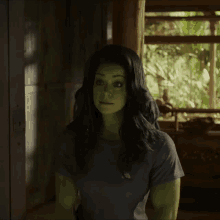 a woman with green hair and muscles is wearing a grey shirt