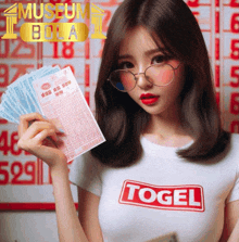 a woman wearing a shirt that says ' togel ' on it holds a lottery ticket