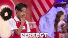 a young boy stands in front of a sign that says perfect on it