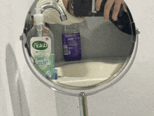 a person is taking a picture of themselves in a mirror with a bottle of nislab hand soap