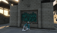 a man sits on the ground in front of a brick wall with the word gimosis written on it