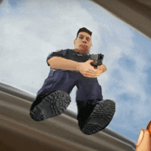 a man holding a gun while sitting on a roof