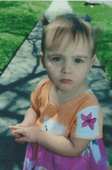 a little girl with a pink flower on her shirt