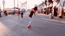 a woman in polka dot pants is dancing on a sidewalk in front of a sign that says ' ice cream '