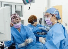 a group of surgeons are operating on a patient in a hospital operating room .