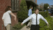 a man in a white shirt and tie is running with his arms outstretched in front of a building that says comedy central