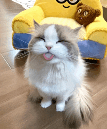 a cat with its tongue hanging out is sitting in front of a yellow minion chair