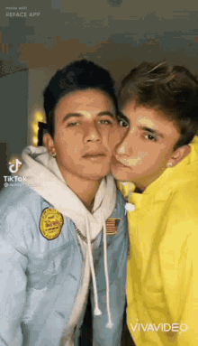 two young men are posing for a picture together and one of them is kissing the other on the cheek .