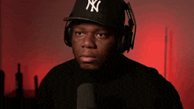 a man wearing headphones and a ny hat is sitting in a chair in front of a red light .