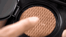 a close up of a person 's finger touching a cushion foundation