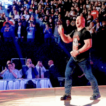 a man in a black shirt with a skull on it is standing on a stage in front of a crowd