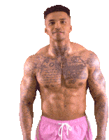 a shirtless man in pink shorts has a tattoo on his chest