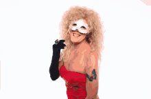 a woman wearing a red dress and a white mask with a butterfly tattoo on her arm