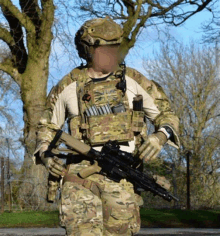 a soldier in a camouflage uniform holds a gun