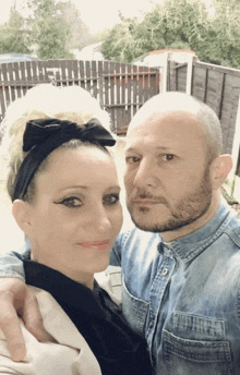 a man and a woman posing for a picture with a fence in the background