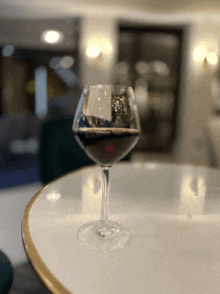 a glass of wine on a table with a blurry background