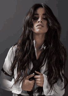 a woman with long dark hair wearing a white shirt and black tie