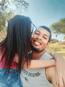 a woman kisses a man who is wearing a lacoste original shirt