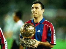 a man in a kappa shirt holds up a soccer ball