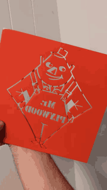 a person is holding a red piece of paper with a drawing of a man and the words " i am 100 % " on it