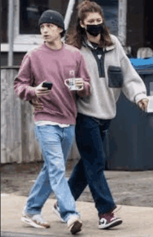 a man and a woman are walking down a street . the woman is wearing a mask .