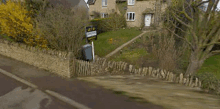 a house with a stone fence and a sign on the side of it .