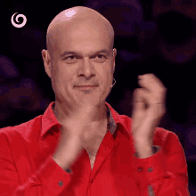 a bald man in a red shirt applauds with a white circle in the corner