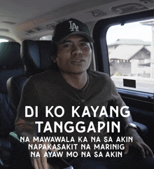 a man wearing a la hat sitting in a car