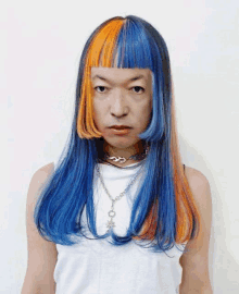 a man with blue and orange hair is wearing a necklace