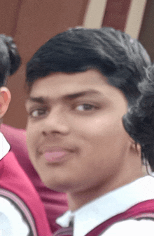 a close up of a young man 's face with a red shirt on