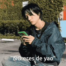 a man in a blue jacket is looking at his phone with the caption " no eres de yao " on the bottom