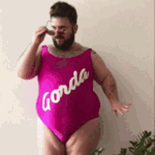 a man with a beard is wearing a pink swimsuit that says gorda on it .