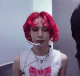 a woman with red hair is wearing a white tank top with a heart on it