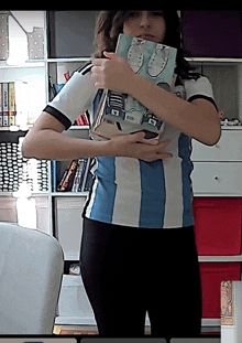 a person wearing a shirt that says ' argentina ' on it holding a book