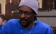 snoop dogg is wearing a gray beanie and glasses and a blue sweater .