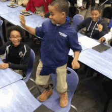 a boy wearing a blue shirt that says ' columbia ' on it stands in front of a group of children