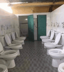 a row of toilets in a bathroom with a green door .