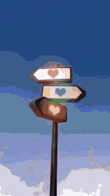 a street sign with three arrows pointing in different directions with hearts on them