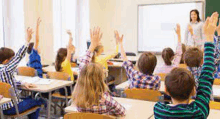 a group of children are raising their hands in a classroom in front of a teacher .