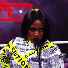 a woman is wearing a newspaper shirt with a yellow caution tape around her neck