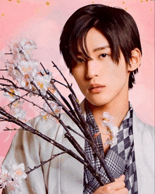 a young man is holding a branch of flowers in his hand