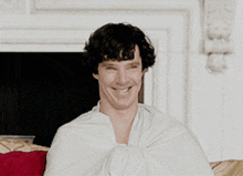 a man wrapped in a white cloth smiles for the camera