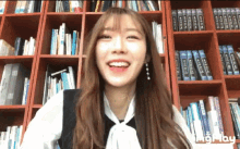 a woman is smiling in front of a bookshelf that has a book titled ' a brief history of the world '