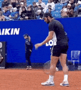 a man is holding a tennis racquet on a court in front of a sign that says " akin "