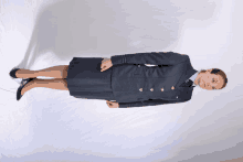 a woman in a blue uniform with gold buttons is standing on a white background