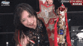 a woman is holding a trophy and wearing a belt that says stardom to the world